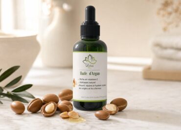 Huile d'argan de Lotus Bio sur un plan de marbre clair, avec sa matière première autour, en lumière naturelle douce